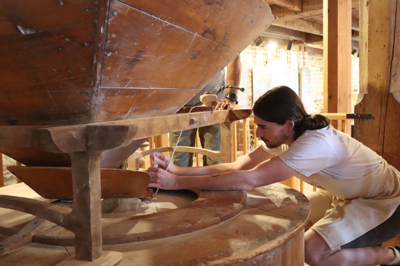 A young child reaches up to touch the wooden pestle on the ground floor of the mill