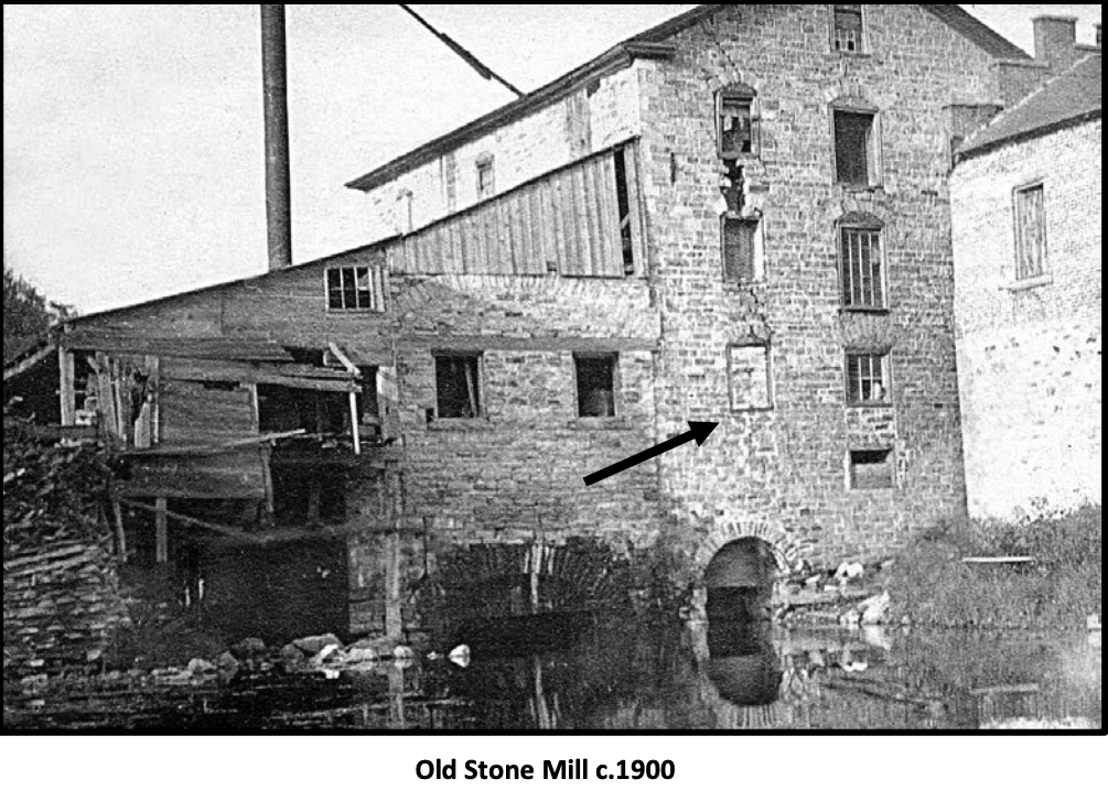 The Old Stone Mill c. 1900 — black and white photograph from across the mill pond showing the full limestone structure