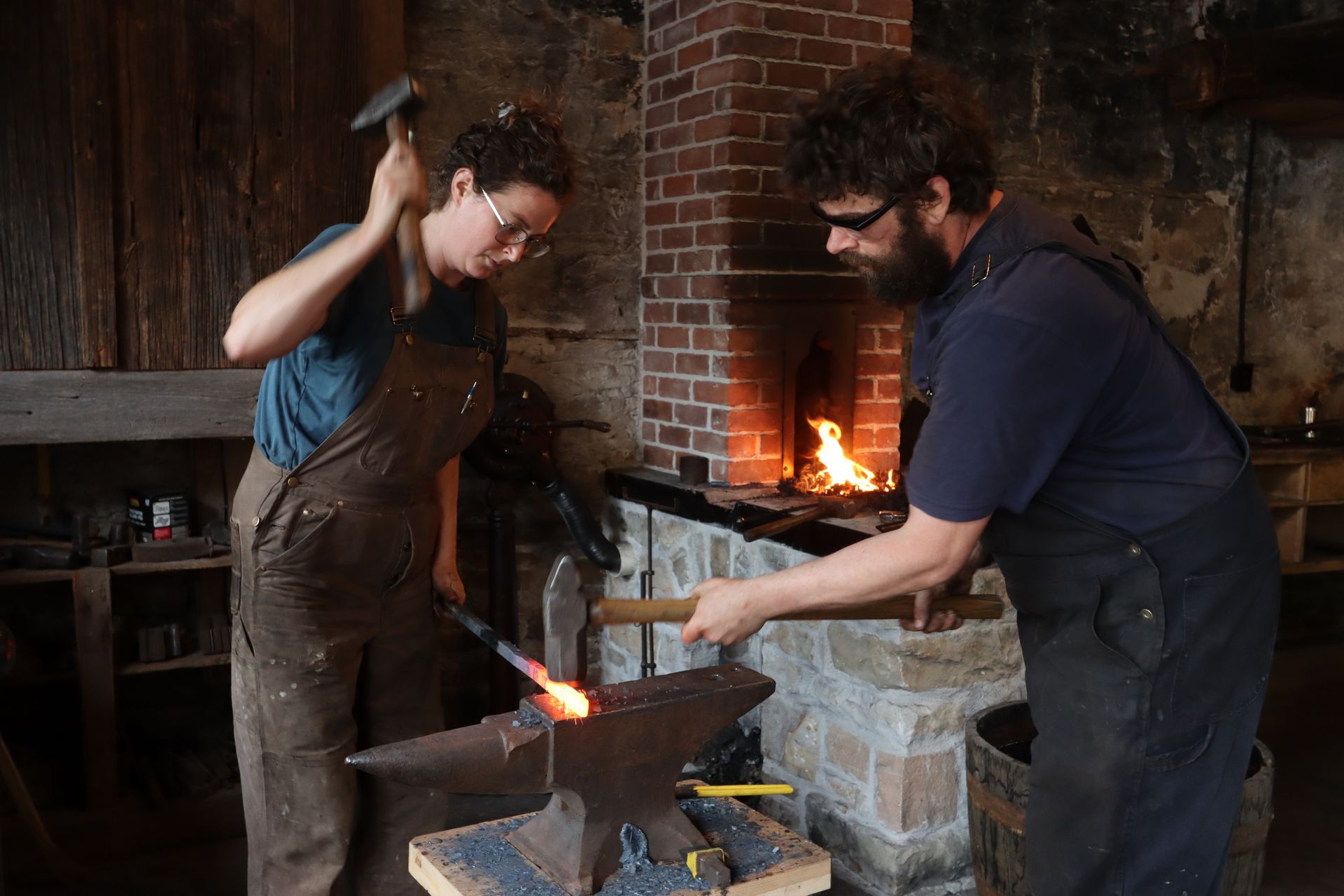 A glowing iron blade on the anvil, held in a gloved hand at the forge