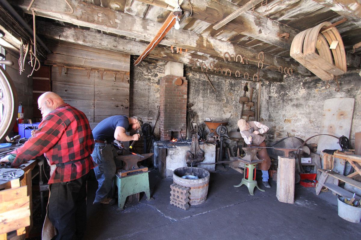 Three blacksmiths working together at the forge, September demonstration